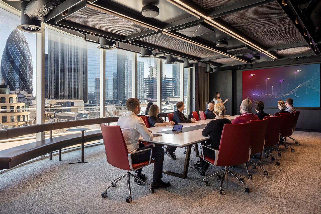 Business presentation taking place in a technology-enabled boardroom with floor-to-ceiling windows and LED videowall.