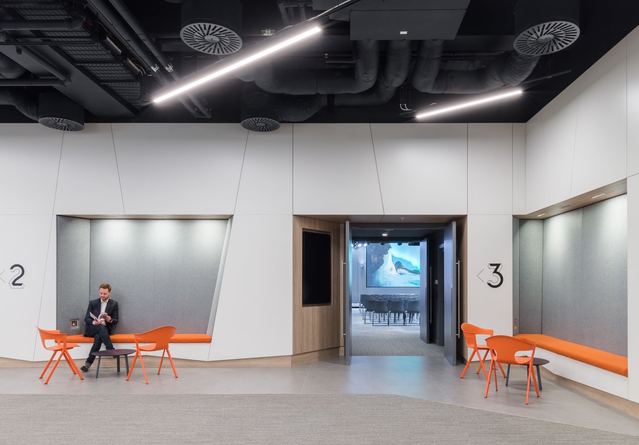 Modern workplace lounge area with built-in seating, meeting room access and informal collaboration spaces in a contemporary office environment