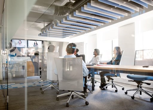 Employees in a large meeting room on a video call 